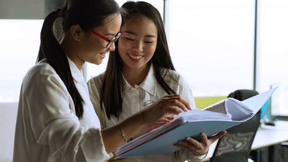 women looking at a binder together